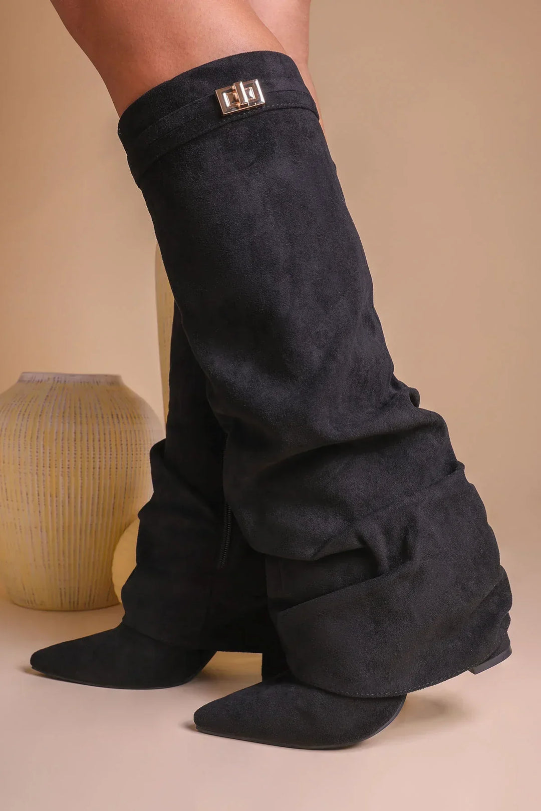 Bota slouch feminina em pose lateral, bico pontiagudo e salto baixo, couro vegano.