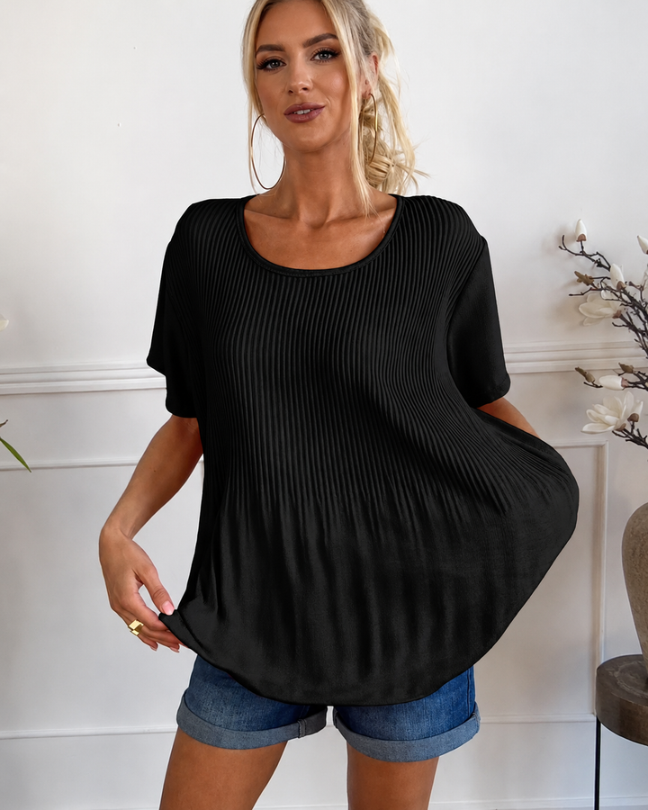 Modelo usando blusa plissada feminina elegante. Decote redondo, ideal para um look casual de verão. Moda versátil.
