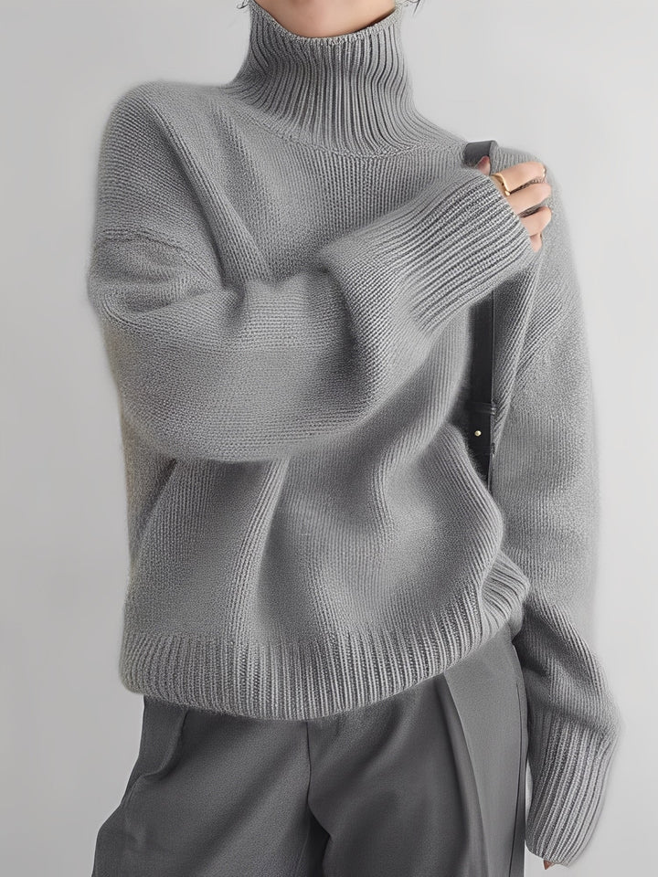 Suéter feminino quente de inverno com gola alta e caimento solto. Roupa elegante e confortável para dias frios.
