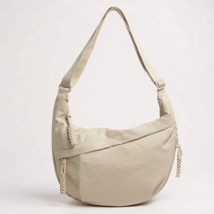 Mulher usando bolsa de ombro Aria de nylon, prática para carregar essenciais no dia a dia.