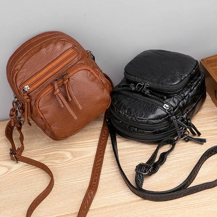 Mala de ombro feminina casual em pele macia preta, acessório elegante e prático para o dia a dia.