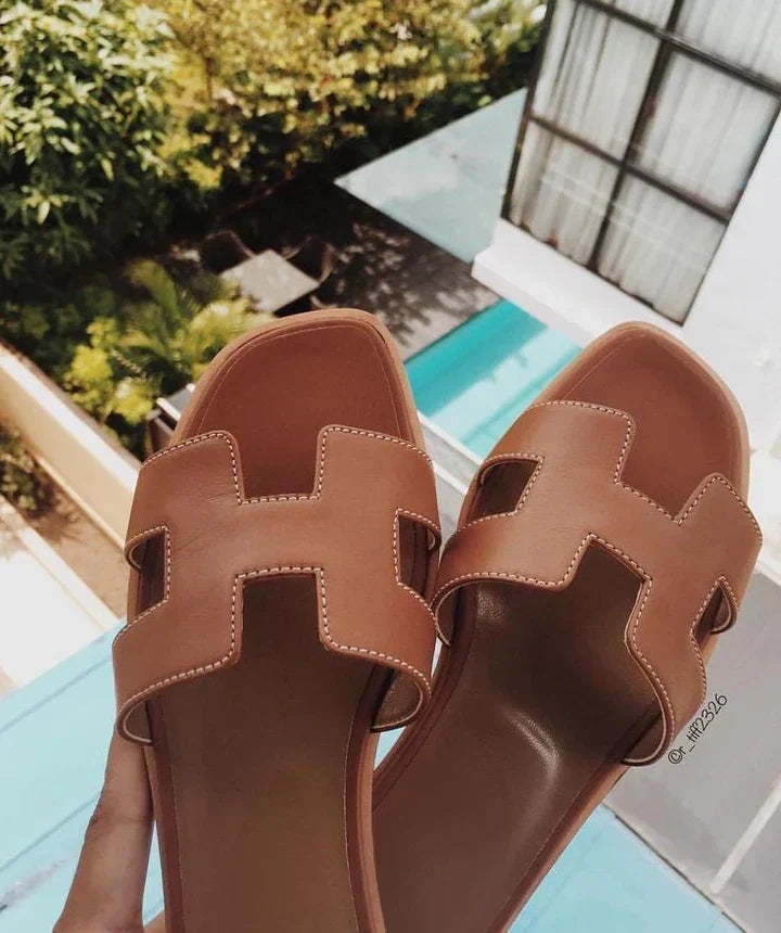 Par de sandálias de couro femininas com tacão baixo e correia H, calçado confortável e elegante para o verão.