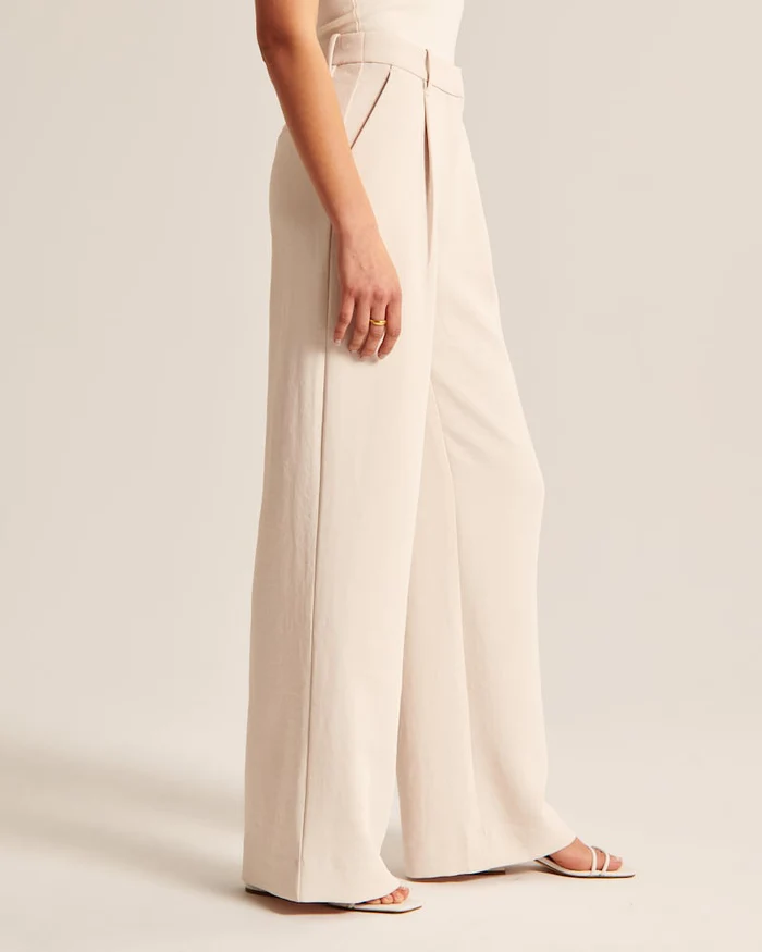 Detalhe da calça feminina bege de perna larga à medida. Conforto, estilo e qualidade alfaiataria.
