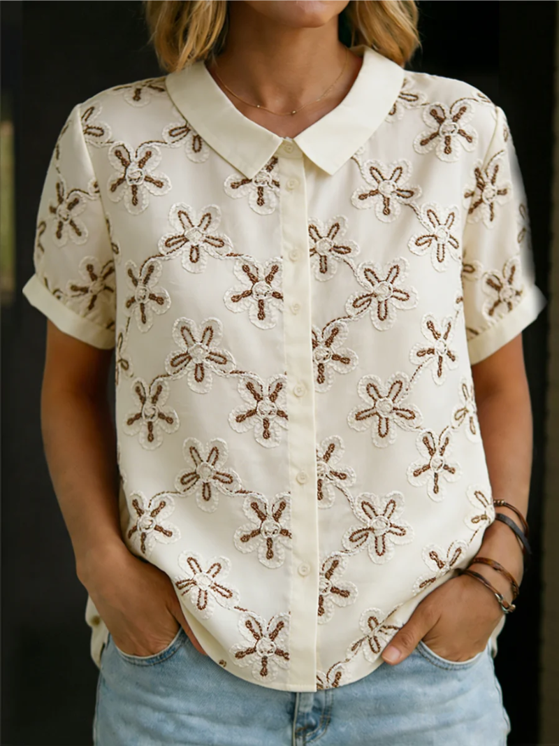 Blusa feminina branca elegante com bordado floral na gola, mangas curtas. Ideal para um look casual de verão.