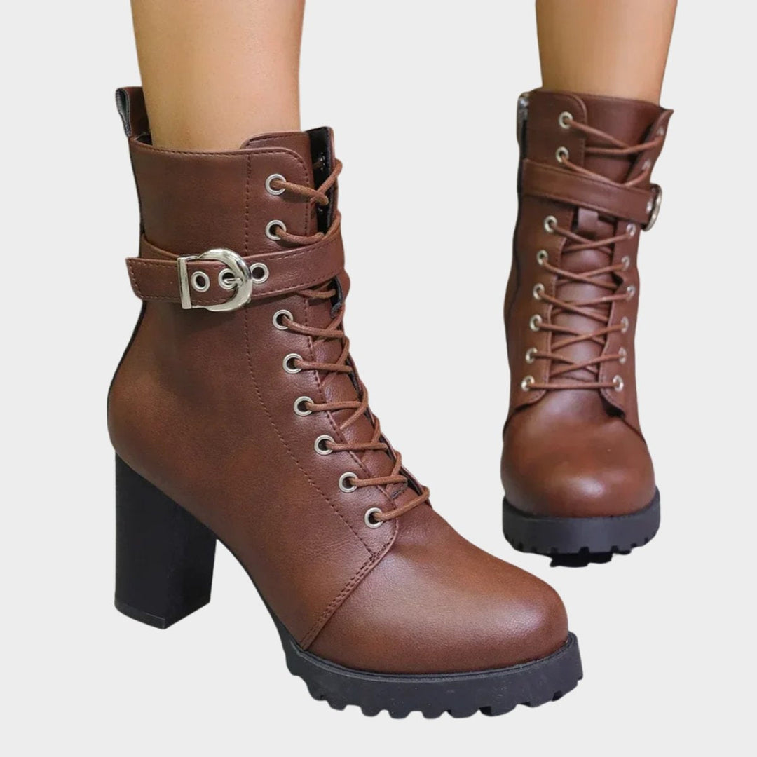 Botins femininos pretos com salto bloco robusto, fivela decorativa e atacadores. Estilo urbano.