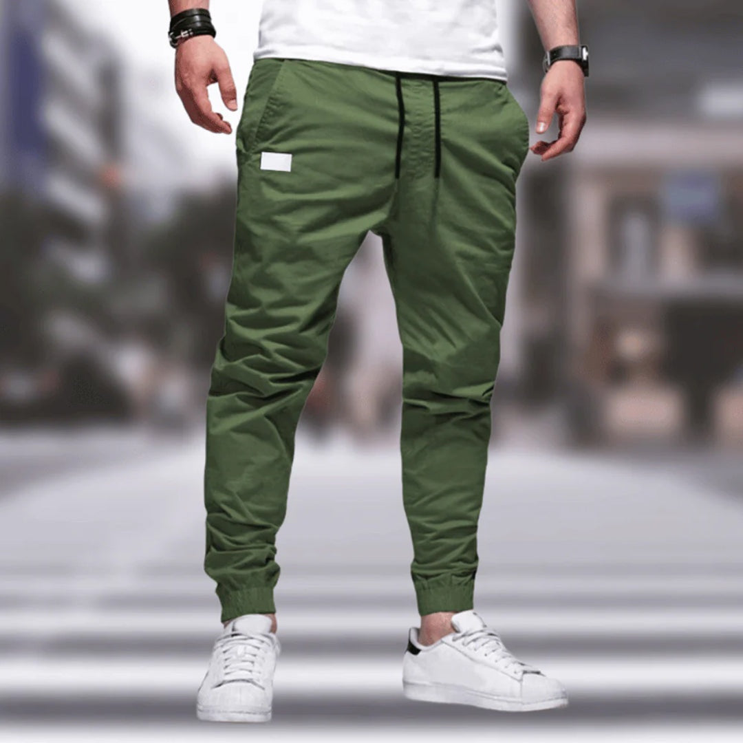 Homem veste calças cargo masculinas confortáveis com cintura elástica, estilo urbano e bolsos laterais para praticidade.