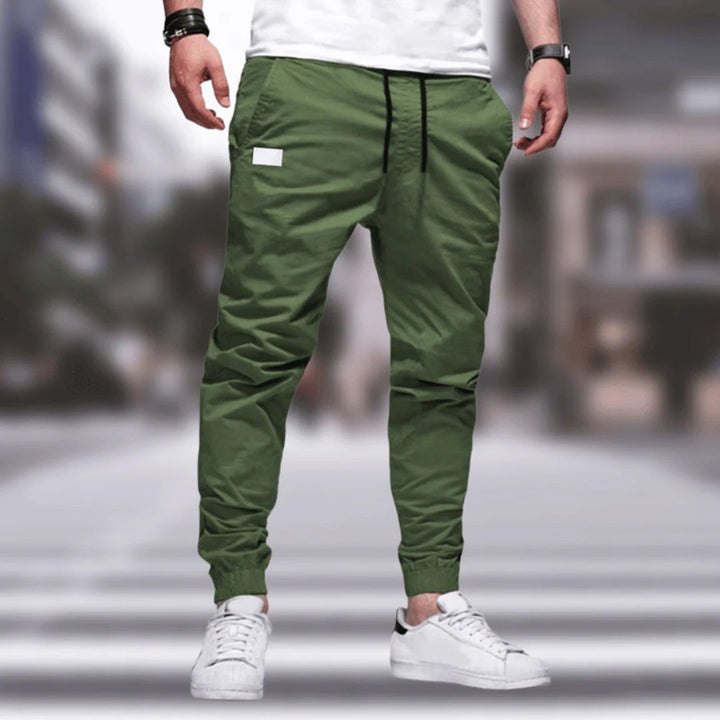 Homem veste calças cargo masculinas confortáveis com cintura elástica, estilo urbano e bolsos laterais para praticidade.