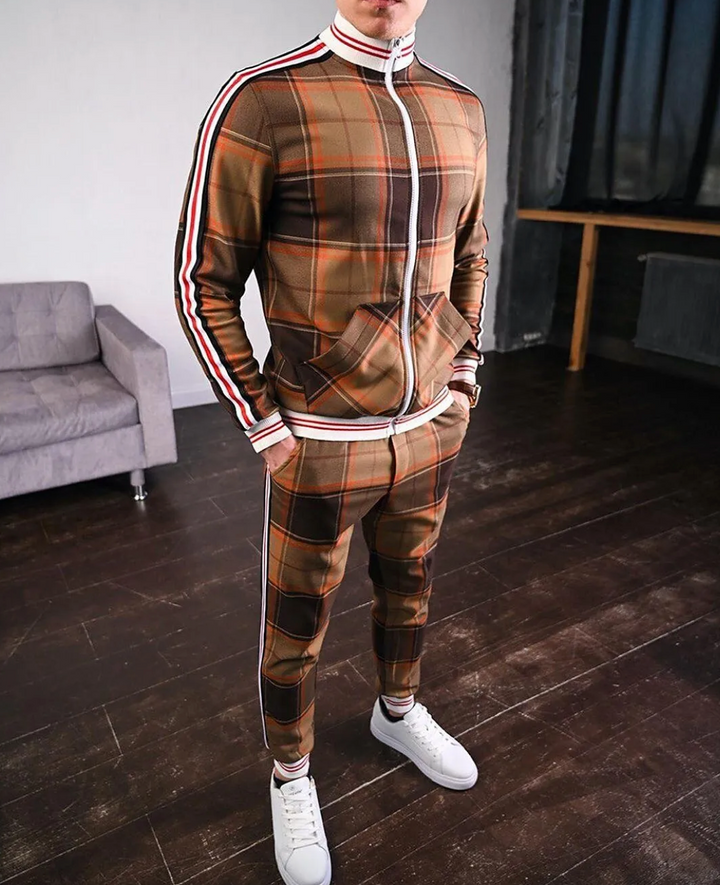 Homem veste conjunto desportivo xadrez com casaco e calças, ambos com riscas laterais. Estilo sportswear.