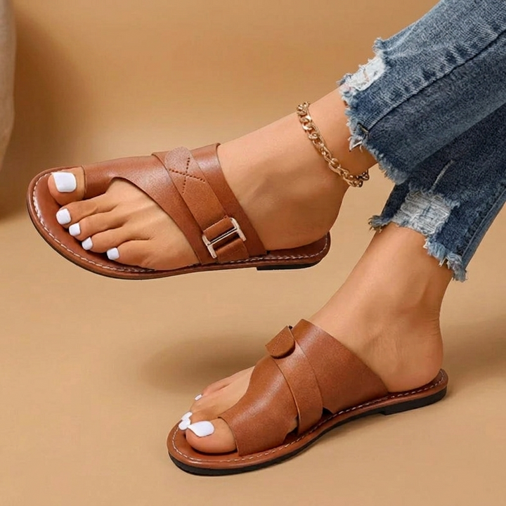 Detalhe das tiras cruzadas das sandálias rasas Cristina para mulher, sinónimo de estilo, conforto e casualidade.