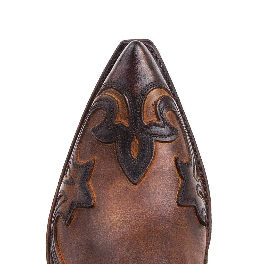 Detalhe da textura do couro da bota feminina cano curto, estilo vaqueira marrom, com bico fino.