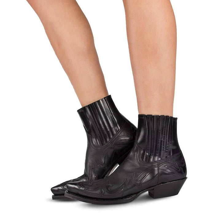 Bota vaqueira feminina marrom de couro, cano curto e bico fino, detalhe lateral, calçado de moda outono.