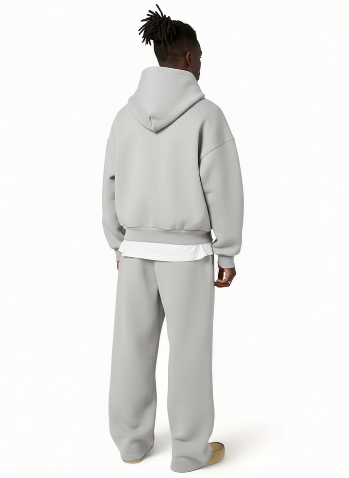 Homem veste conjunto treino com hoodie capuz e calças perna larga pretas, ideal para um look urbano e descontraído.