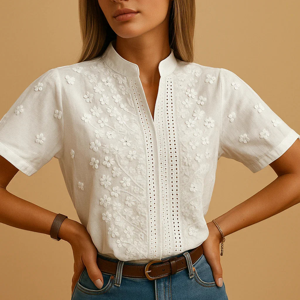 Detalhe da blusa feminina Cambria branca com bordado floral na gola fenda e mangas bufantes, moda verão.