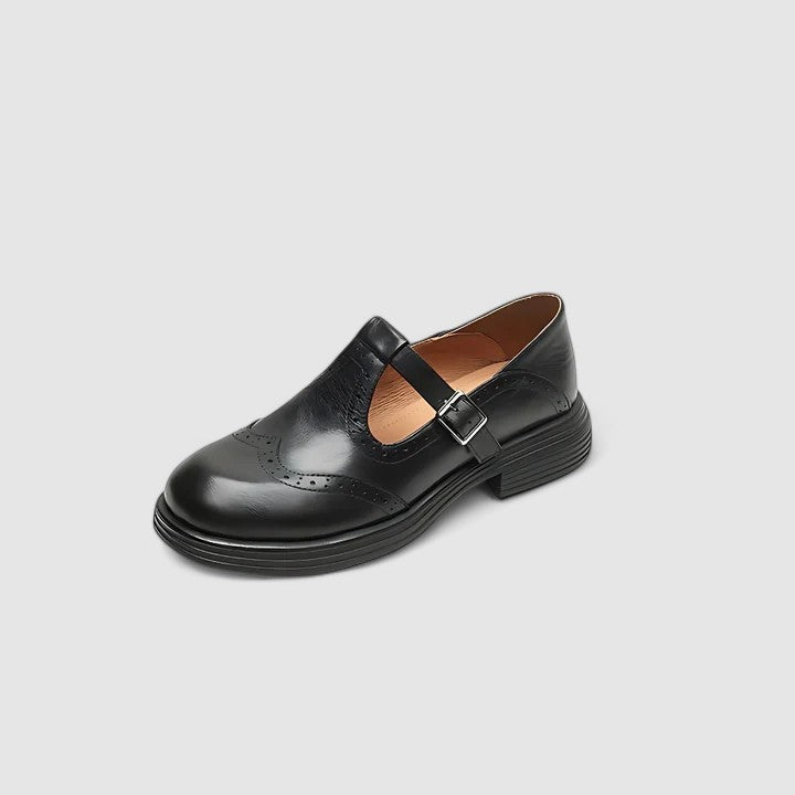 Close-up do detalhe brogue decorativo em sapatos Oxford Mary Jane femininos com fivela.