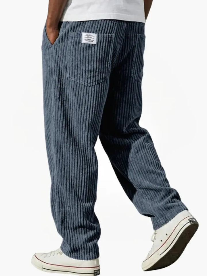 Homem a usar calças de bombazine, corte largo. Look casual e estiloso para outono/inverno.