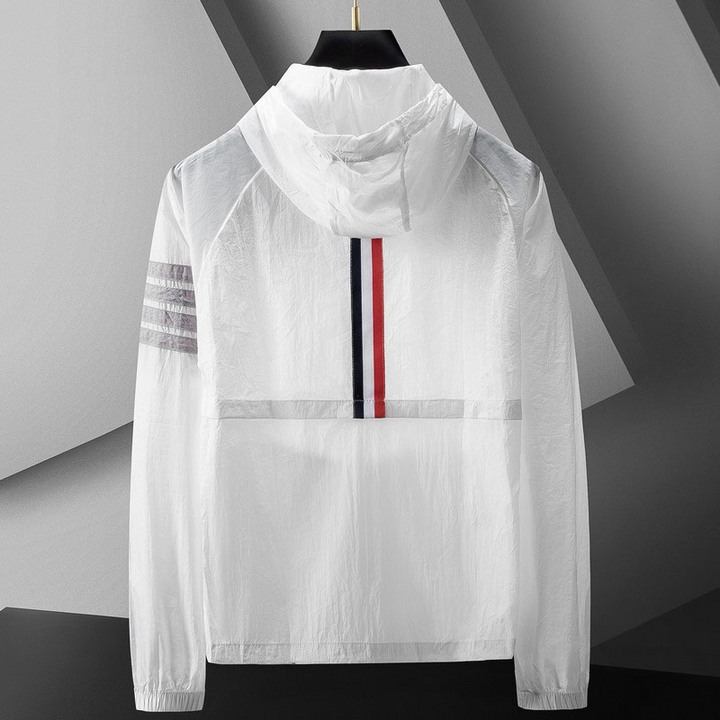 Homem veste corta-vento leve e desportivo com capuz e riscas. Roupa casual e funcional para exterior.