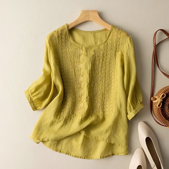 Detalhe de blusa feminina versátil com bordado delicado na gola e mangas, perfeita para o verão e primavera.
