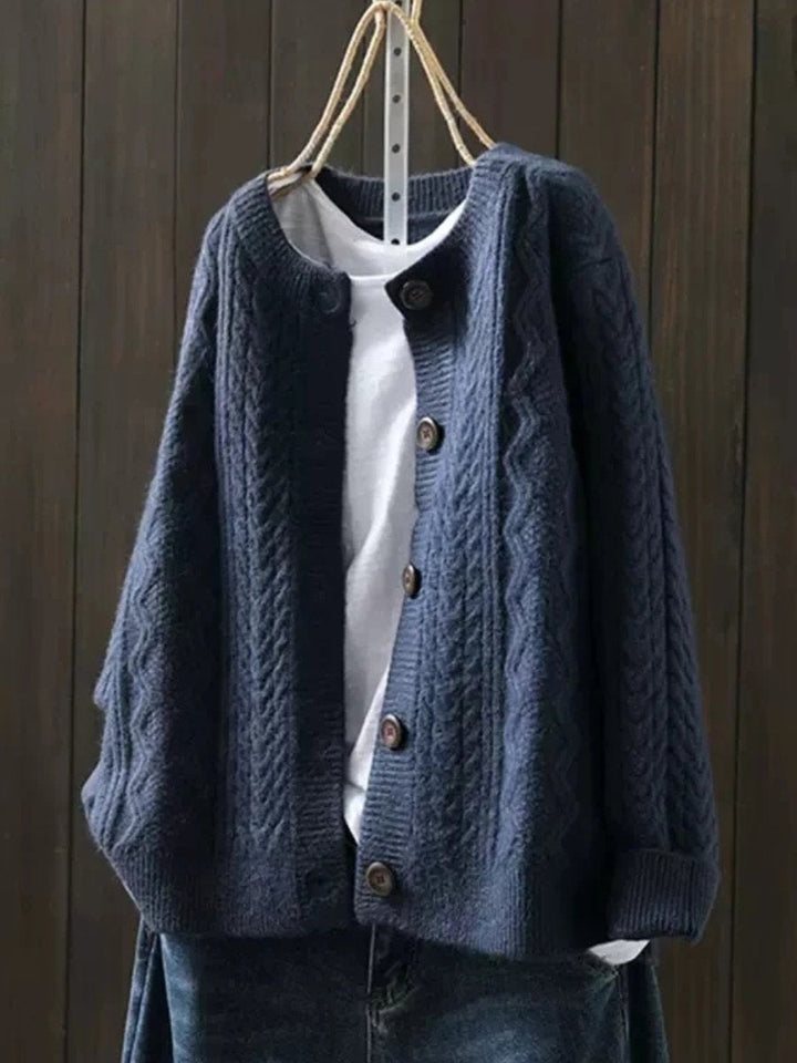 Casaco feminino de malha trança com botões, modelagem oversized. Peça de moda versátil para dias frios.