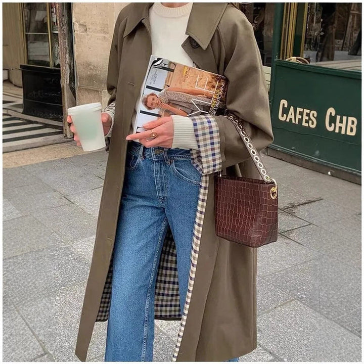 Mulher a vestir gabardina oversize com forro xadrez. Casaco comprido elegante e confortável.