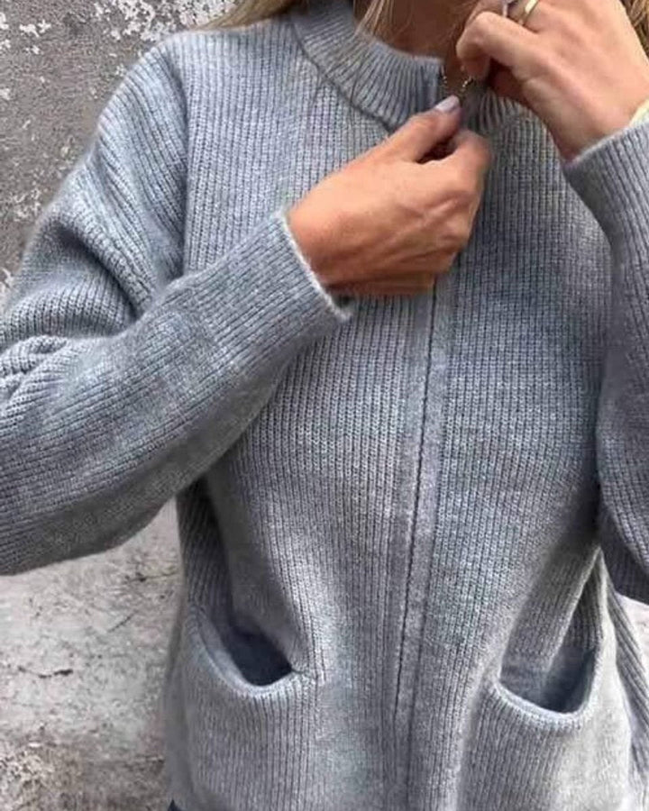 Mulher veste casaco de malha elegante com fecho frontal e bolsos laterais, perfeito para um look versátil.