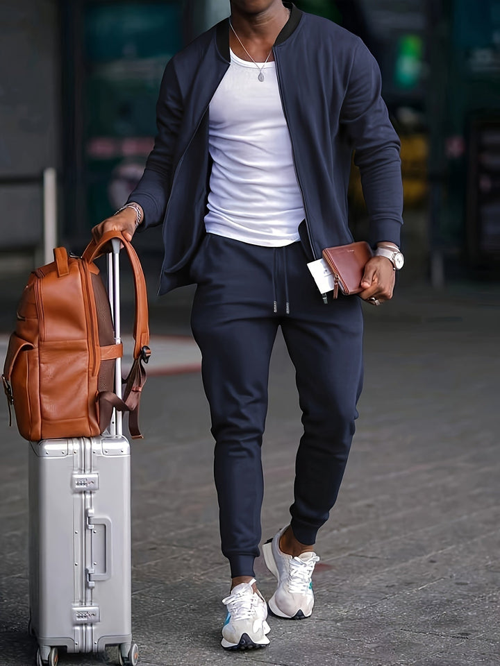 Homem veste conjunto de treino jogger cinza com jaqueta zip, ideal para exercícios e uso casual masculino.