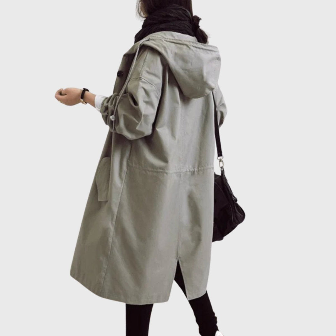Elegante gabardina feminina comprida impermeável, com capuz e corte largo, essencial para moda outono/inverno.
